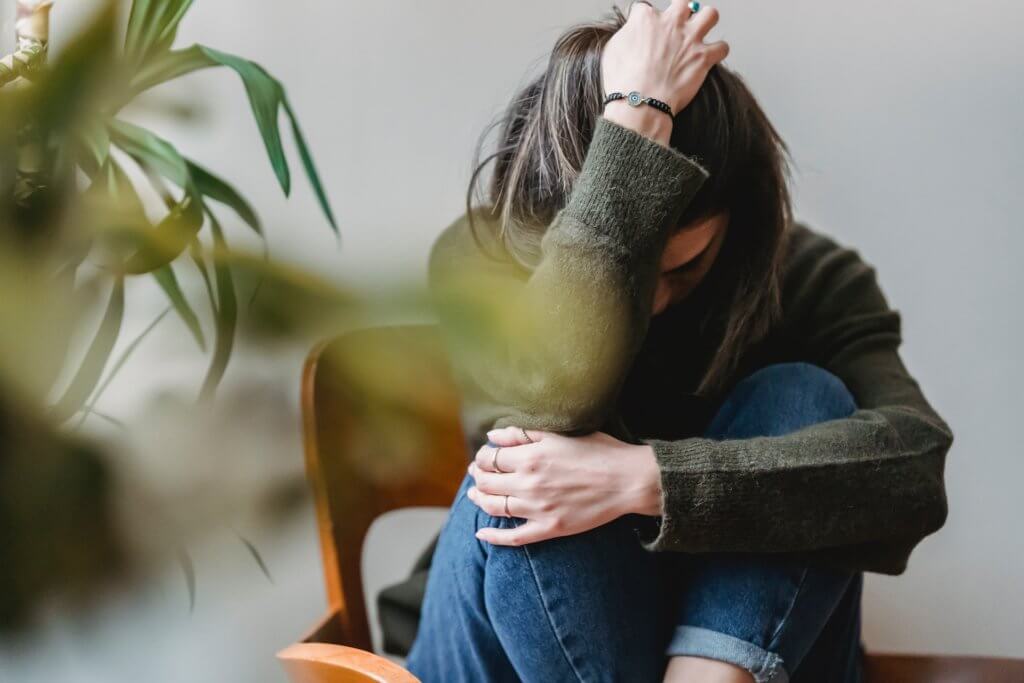 worried woman on a chair behind a plant